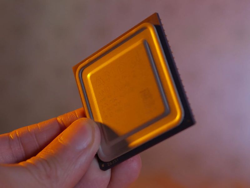 Osoba drži u ruci AMD procesor za komjuteri, neutralna pozadina