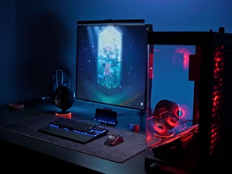 Na slici prikazan gejmerski komjuter, monitor, miš, postavka za miš, slušalice i tastatura