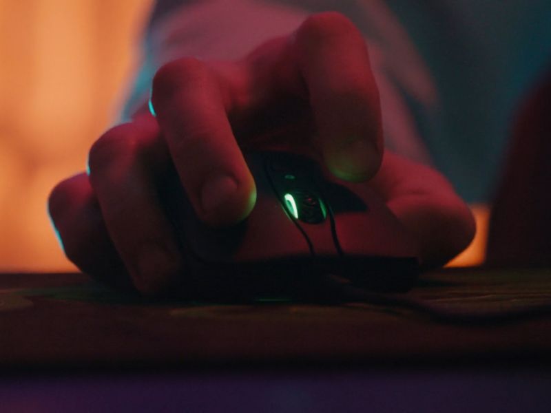 Osoba koristi gaming miš crne boje sa zelenim laserima