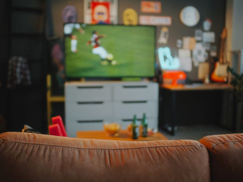 prikaz dnevnog boravka sa tv-om na kom se gleda sportska utakmica